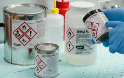 A chemist applies a GHS label to a container.