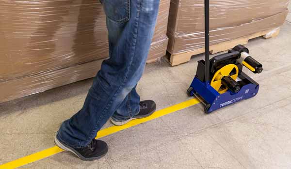 A safety professional installing floor tape using an applicator.