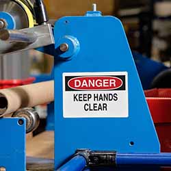 A label on a machine says 'keep hands clear.'