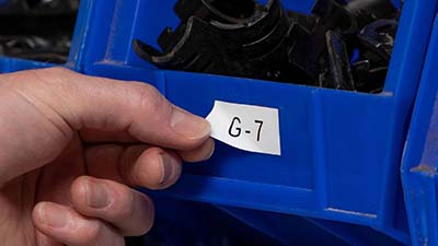 A person adjusts a removable label on a bin.