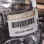 A glass container with a barcode label that identifies it as sterilised.
