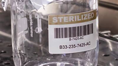 A glass container with a barcode label that identifies it as sterilised.