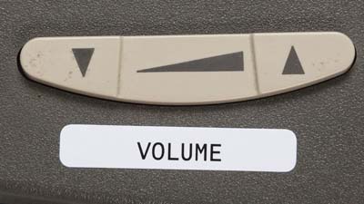 The volume control on a telephone identified with a white label.