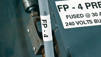 A white label containing electrical information placed on industrial equipment.