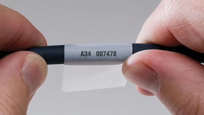 A wrap around label with a printed ID applied to a black cable.